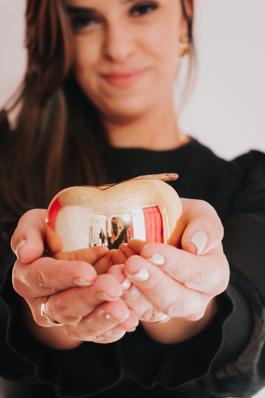 Detalhe das mãos de Bianca Guimarães em gesto acolhedor durante atendimento em grupo